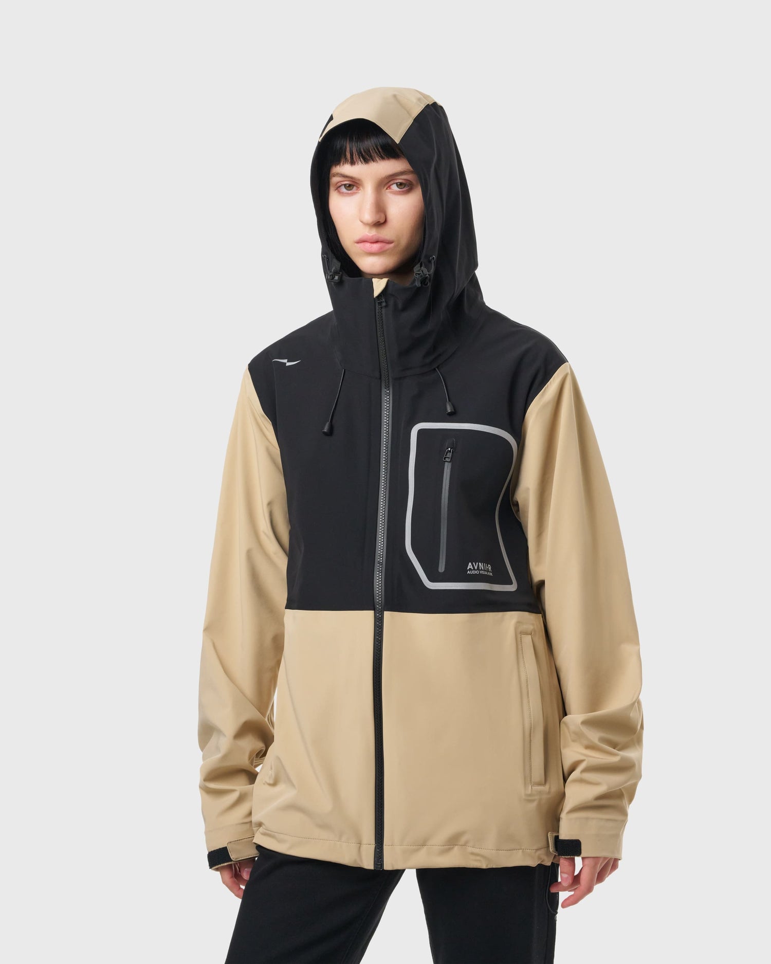 Femme portant la veste Avnier Interlude beige avec capuche, protection contre la pluie, style workwear moderne. - beige